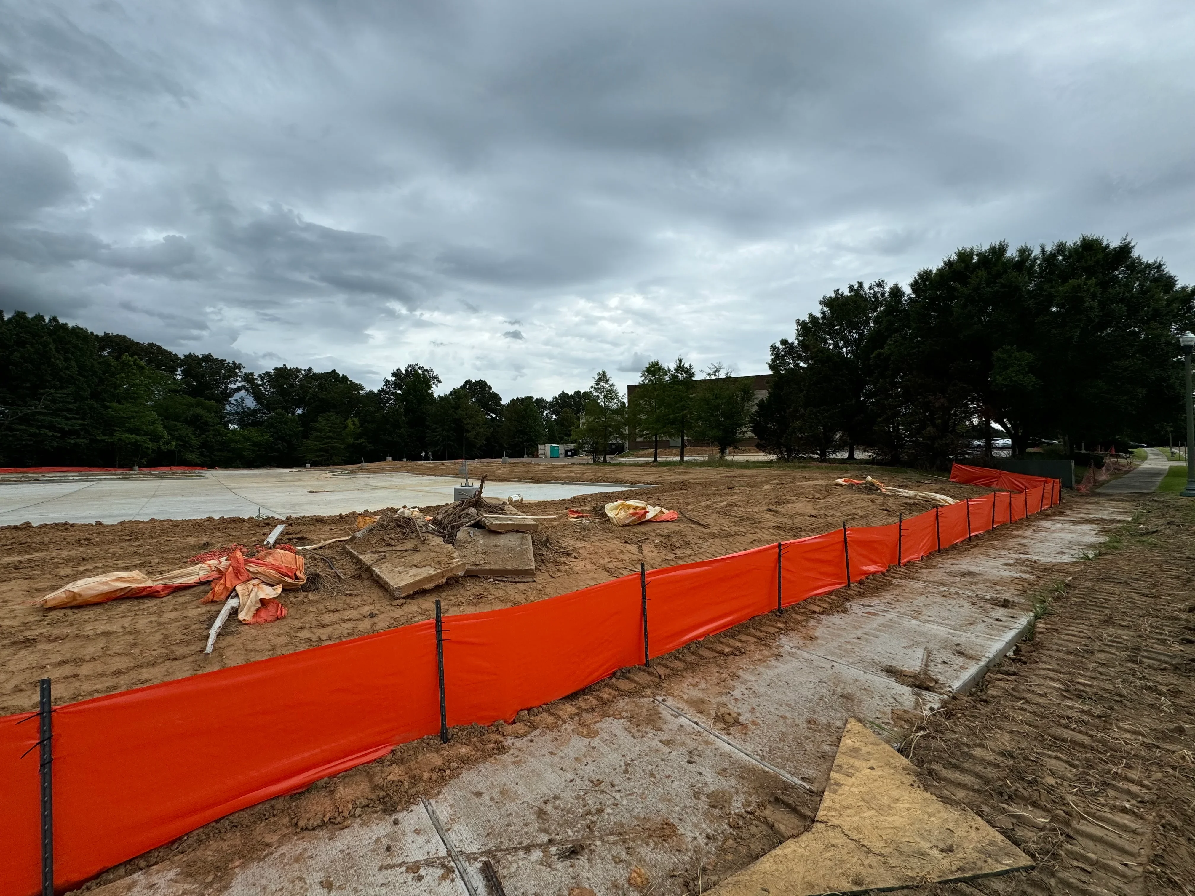 Orange erosion control fencing with stakes installed on bare soil construction site