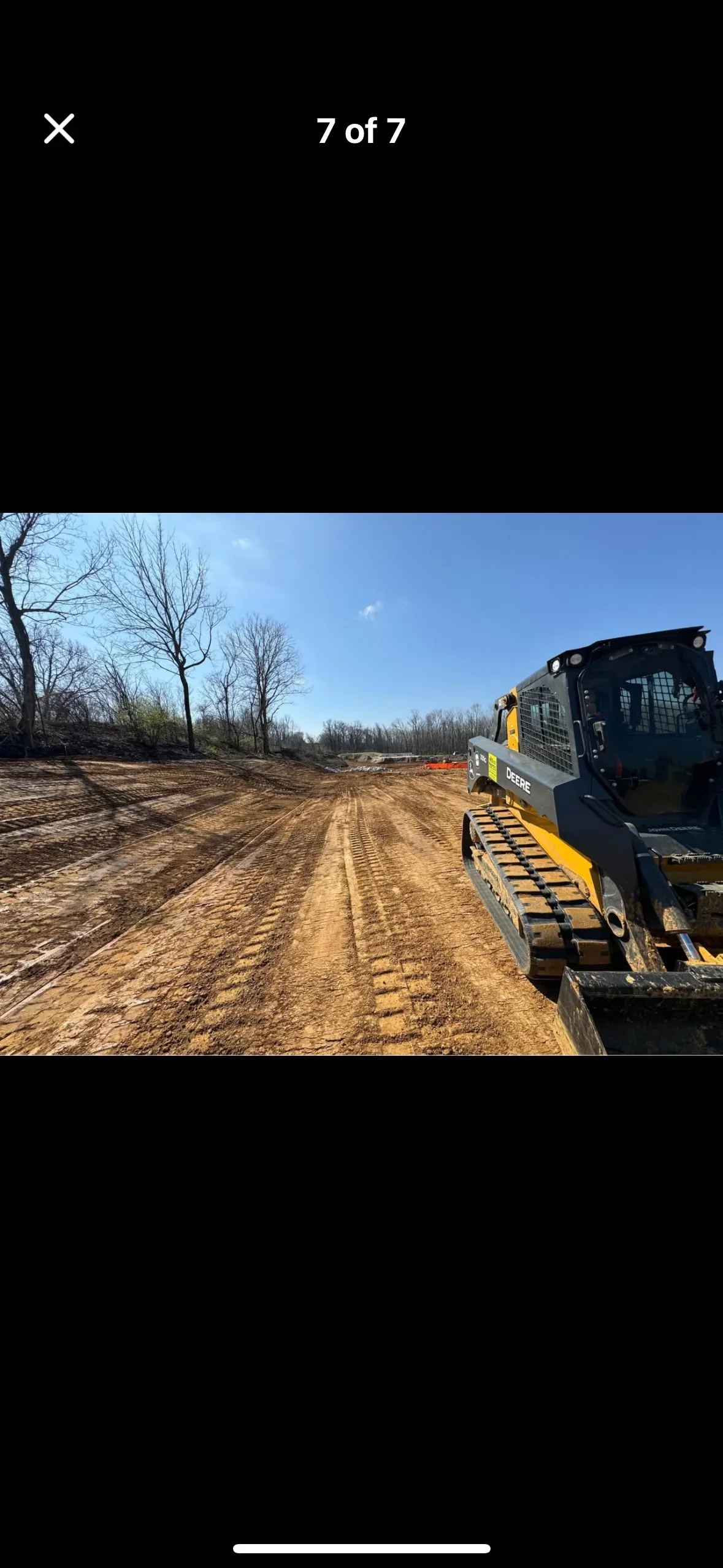 Compact track loader grading and leveling soil on cleared residential property