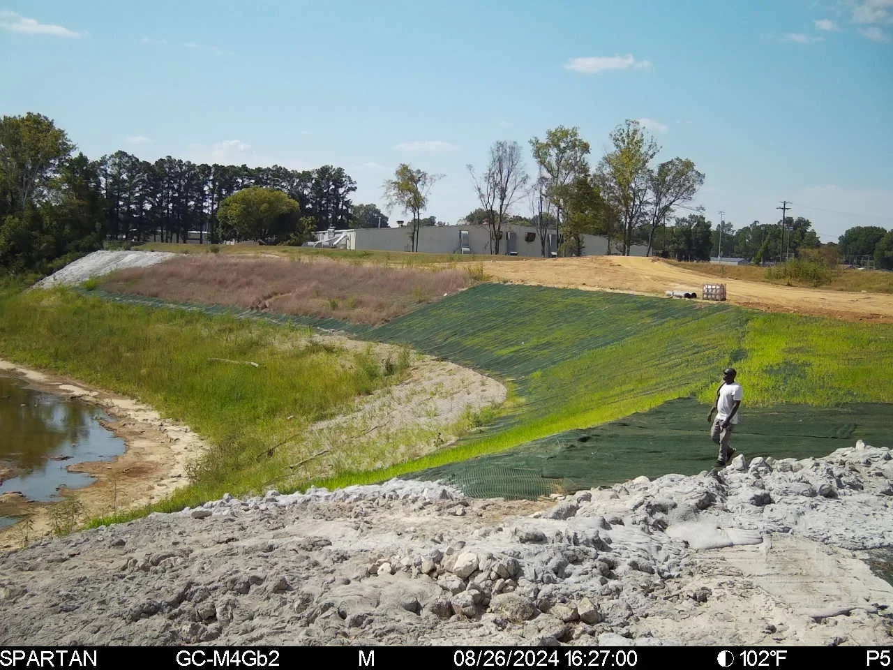 Geotextile fabric erosion control on sloped terrain with rock riprap base and vegetation establishment