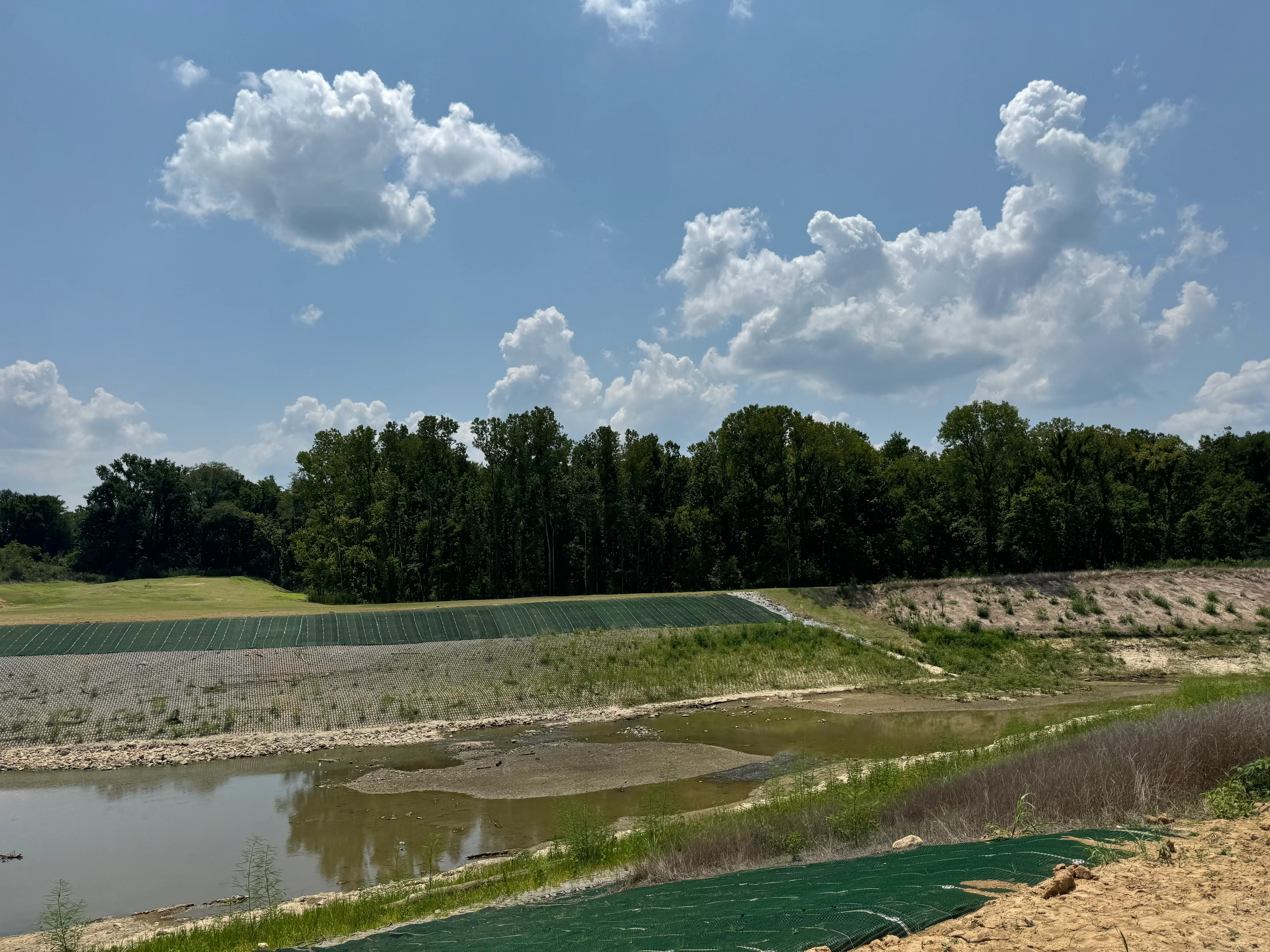 Riverbank erosion control with geotextile matting, riprap, and vegetation along water's edge