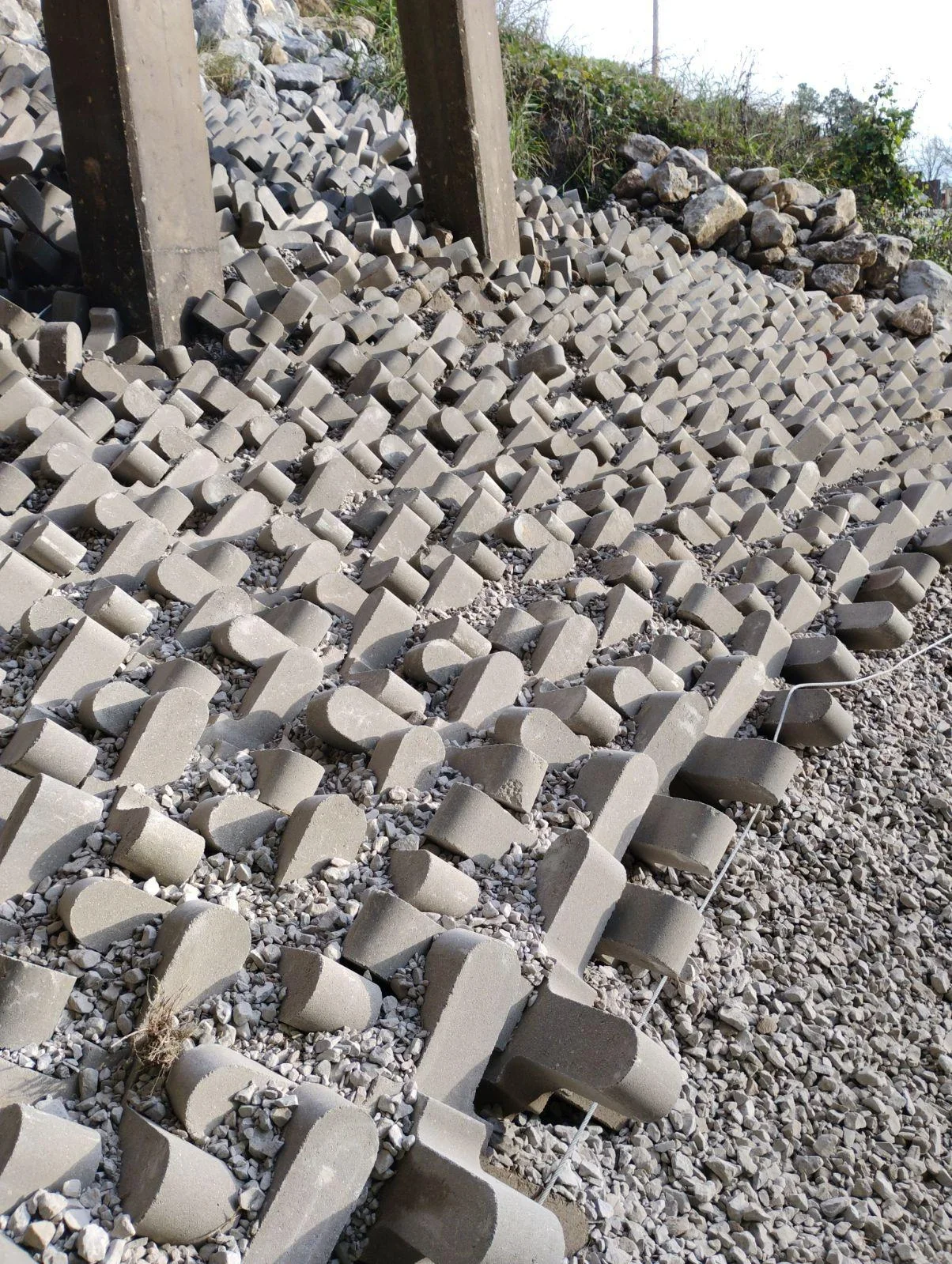 Interlocking concrete erosion control blocks installed in gravel base on sloped terrain