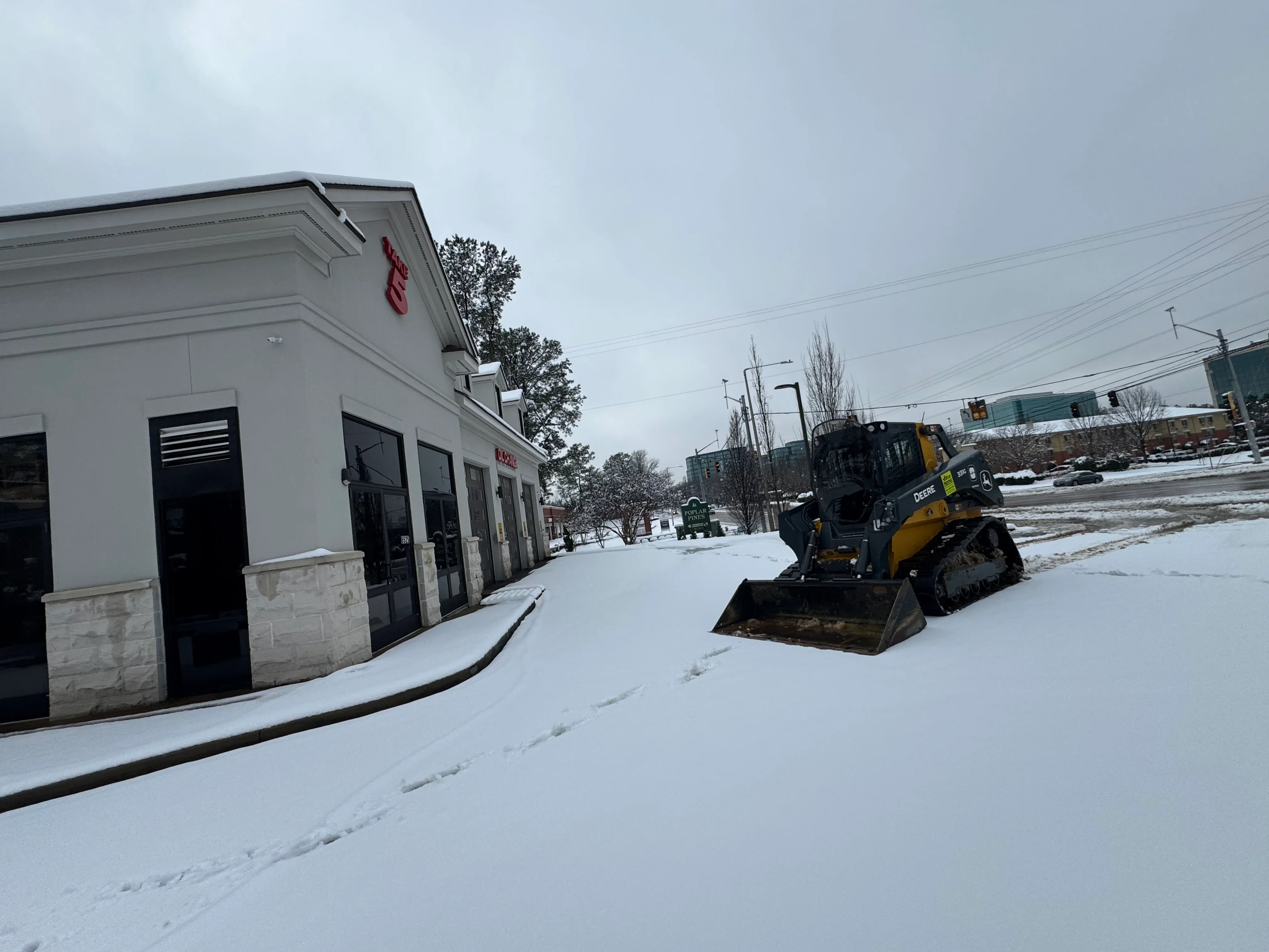 Tracked snow removal equipment clearing snow from commercial parking lot